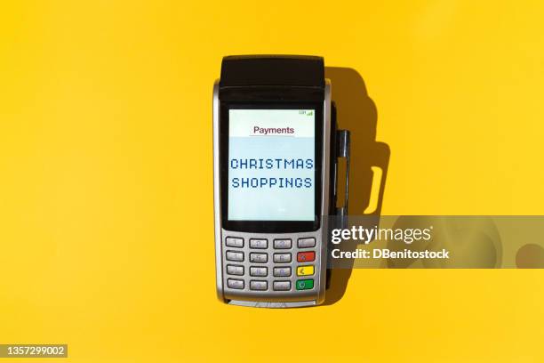 credit card reader with the word 'christmas shopping' on the screen on yellow background. concept of christmas shopping, shops, malls and credit cards. - christmas savings stock pictures, royalty-free photos & images