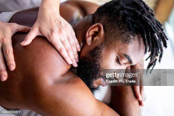 mid adult man receiving massage on shoulders at a spa - massage bildbanksfoton och bilder