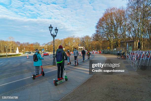 gruppe von menschen fährt elektroroller an einem kalten morgen auf der straße in berlin - mobility as a service stock-fotos und bilder