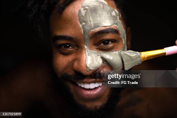 portrait of an adult man doing a facial treatment at a spa - fangoterapia imagens e fotografias de stock