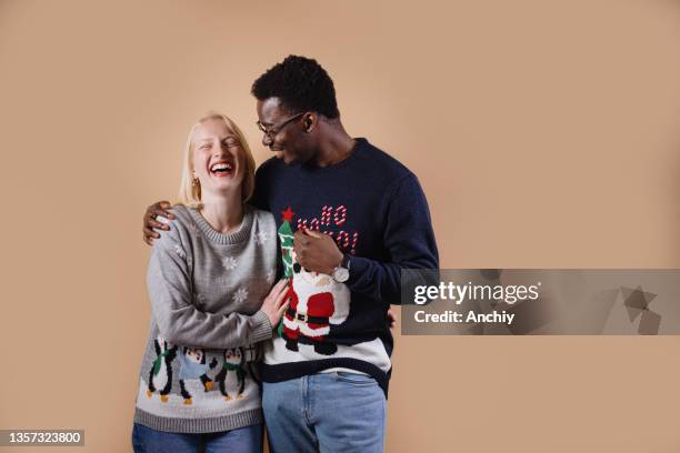 jovem casal vestindo suéteres de natal feios - ugly christmas sweater party - fotografias e filmes do acervo