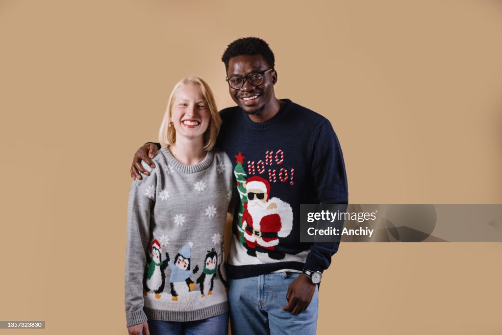 Young couple wearing ugly Christmas sweaters