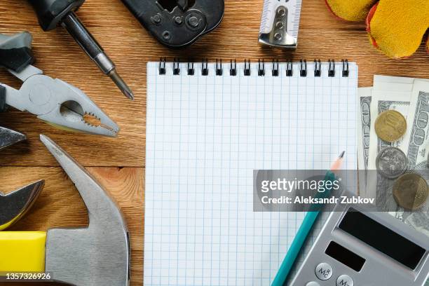 tools for building a house or repairing an apartment, on a wooden background or table. workplace of the foreman. the theme of home and professional repair and construction. notepad and pen, calculator and cash dollars. copy space. - service level high stock pictures, royalty-free photos & images