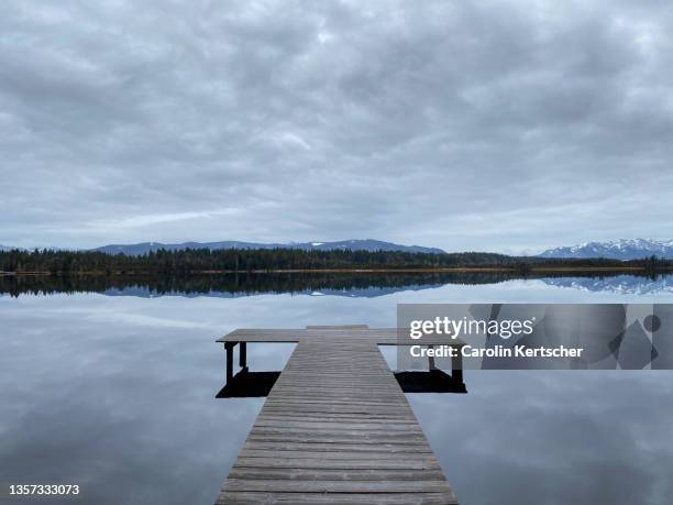wooden stage at lake with reflection and mountain backdrop | bavaria - nieuwjaarsduik stockfoto's en -beelden