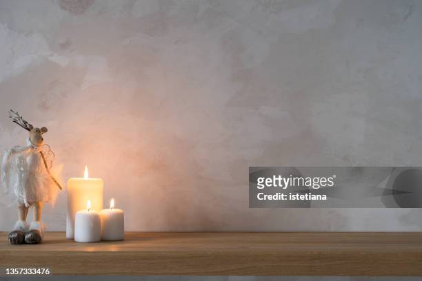 clean home environments. decorative  christmas deer-shaped toy and three white candle - candle white background imagens e fotografias de stock