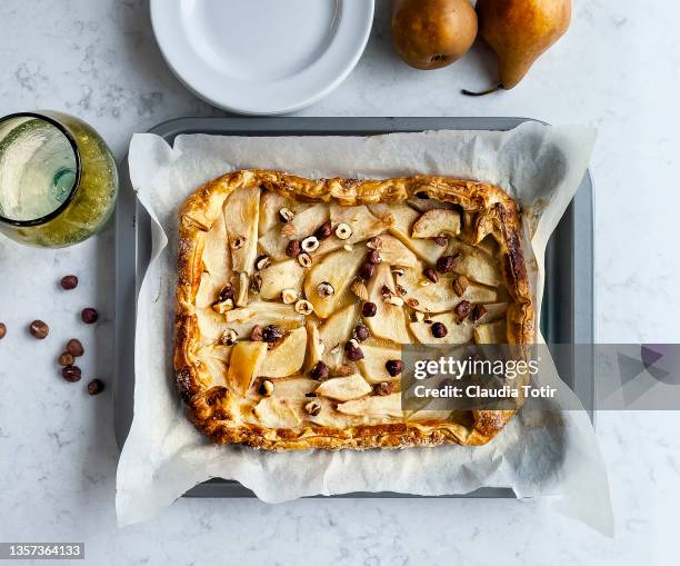 pear tart with hazelnuts on parchment paper on white background - tart dessert stock pictures, royalty-free photos & images