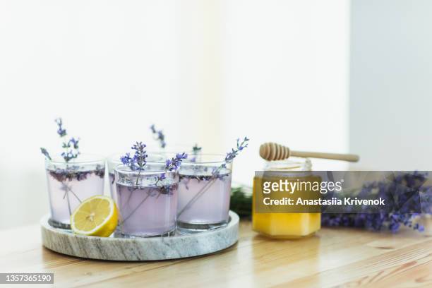 honey, glasses with ice, lemon juice and lavender cocktail on kitchen table. - cocktail recipe stock pictures, royalty-free photos & images