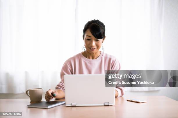 a woman working on a computer at home. - 茅ヶ崎市 fotografías e imágenes de stock