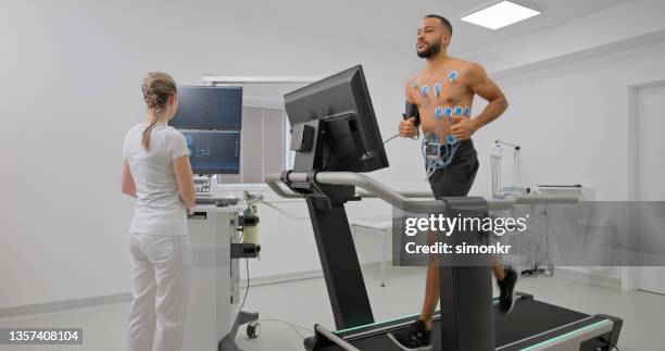 männlicher athlet, der auf einem laufband läuft und einen cardio-stresstest macht - belastungsprobe stock-fotos und bilder