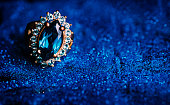 Closeup of luxury wedding ring in dark blue glitter background.