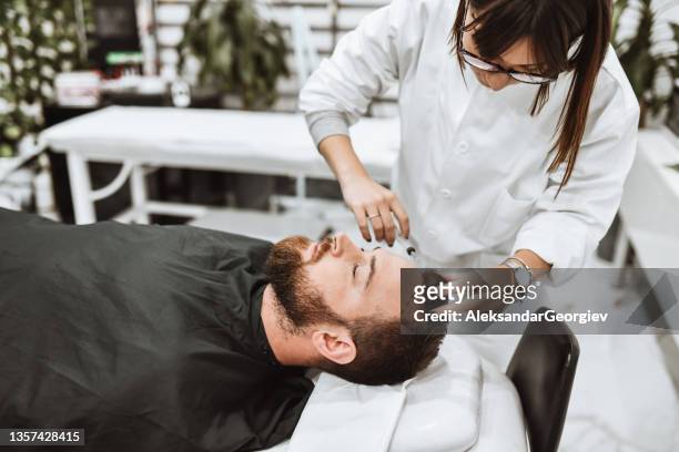maschio che ottiene filler dermici in fronte da un medico femminile - trattamento di bellezza foto e immagini stock