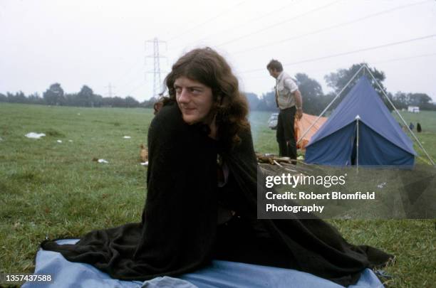 Man sits in the camping field at the first Glastonbury Festival, United Kingdom, September 1970.