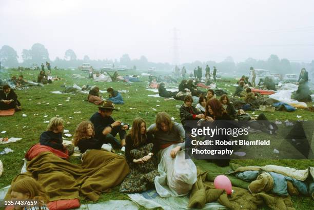 Young people keep warm in the morning mist surrounded by cars and rubbish at the first Glastonbury Festival, United Kingdom, September 1970.