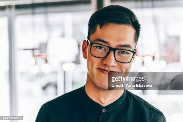 portrait of happy and handsome asian man smiling at camera in public place - korean bildbanksfoton och bilder