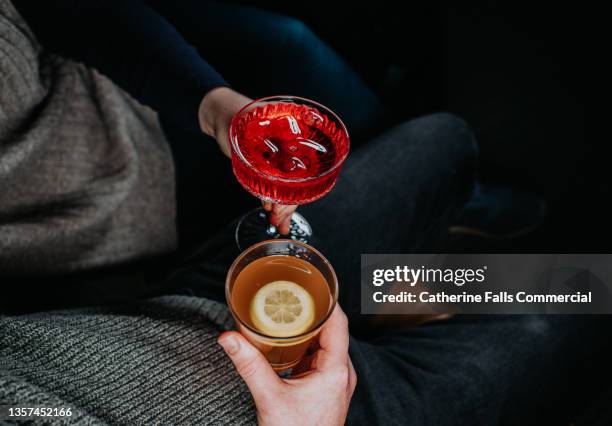 top down image of two people sitting close to each other, holding festive cocktails - cocktail and mocktail stockfoto's en -beelden