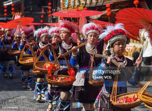 Dong young women holding red umbrellas and carrying food parade to celebrate the new year of Dong ethnic group at Liping County on December 5, 2021...