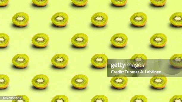 repeated pattern of many sliced ripe kiwi fruits on light green background. - kiwi fruit 個照片及圖片檔