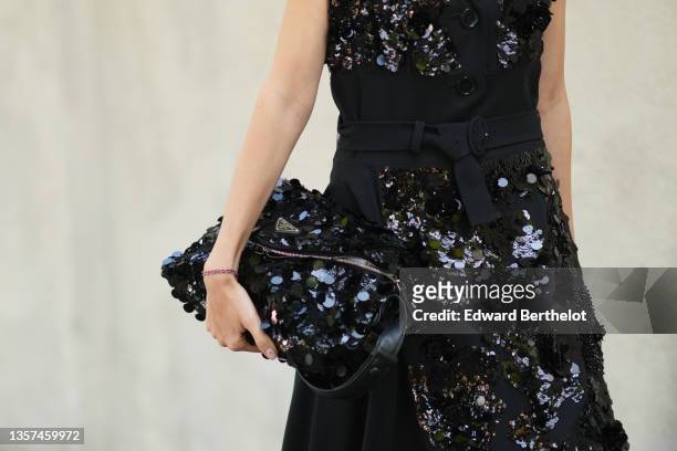 Nataly Osmann wears a black wool belted long dress with large sequined embroidered from Prada, a black shiny leather bag with large sequins...