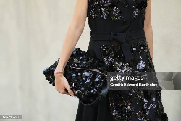 Nataly Osmann wears a black wool belted long dress with large sequined embroidered from Prada, a black shiny leather bag with large sequins...