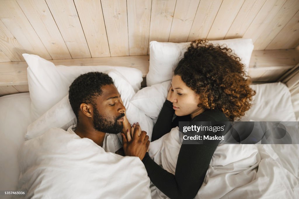 Directly above view of couple sleeping on bed in hotel