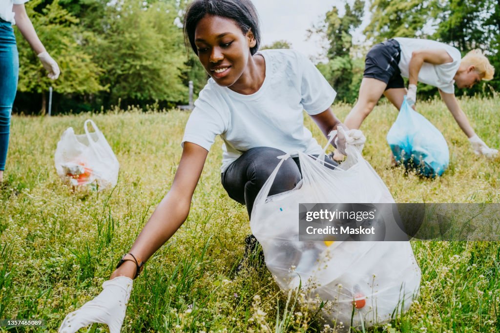 Female and male environmentalists picking up plastic waste at park
