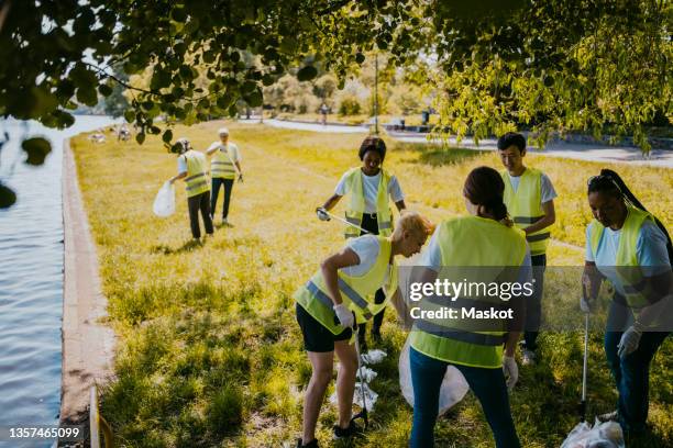 female and male climate activists cleaning plastics at lakeshore - berlin ufer stock-fotos und bilder