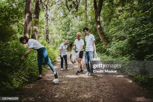 male and female environmentalists picking up garbage in park - topics stockfoto's en -beelden