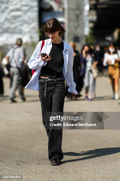 Guest wears a black tank-top, a baby blue and white striped shirt, a red shiny leather with GG monogram print pattern shoulder bag from Gucci, a...