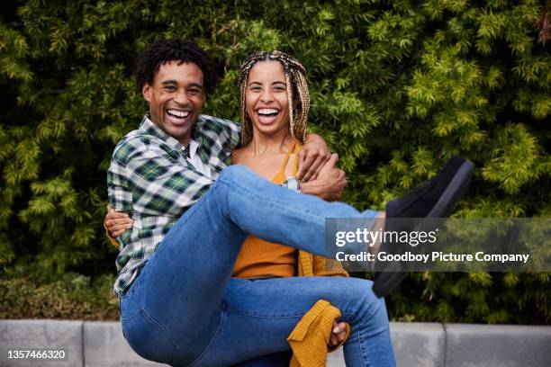 laughing young woman carrying her boyfriend in her arms outdoors - rolwisseling stockfoto's en -beelden