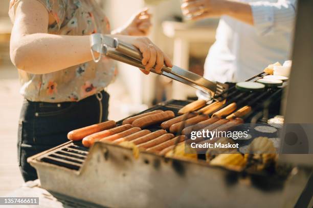 midsection of woman preparing food on barbecue grill during garden party - hot dogs on grill stock pictures, royalty-free photos & images