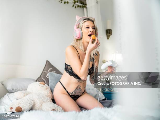 blonde woman playing video games in her bed - eating secret stockfoto's en -beelden