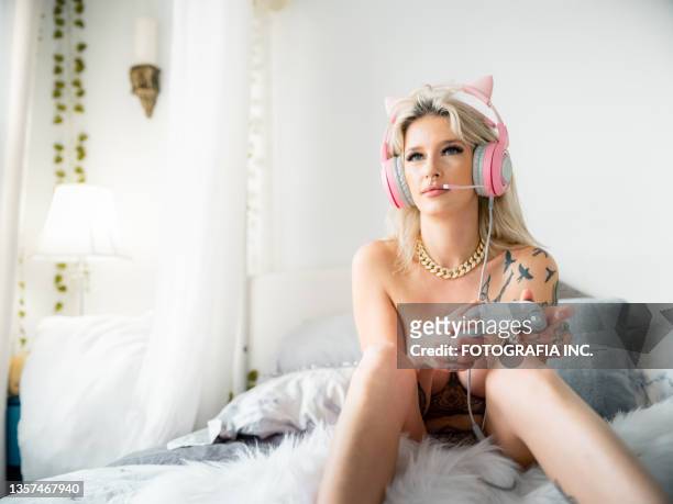 blonde woman playing video games in her bed - womenswear stock pictures, royalty-free photos & images
