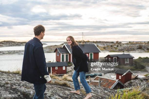 smiling girlfriend playing with boyfriend at island during sunset - stockholm archipelago stock pictures, royalty-free photos & images