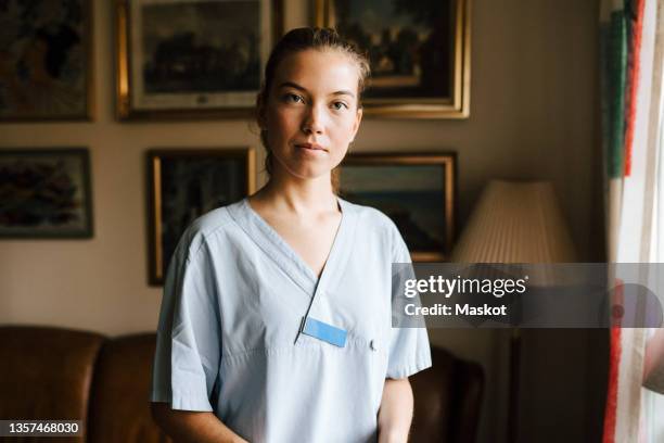 portrait of female nurse in living room at home - nurse serious stock pictures, royalty-free photos & images