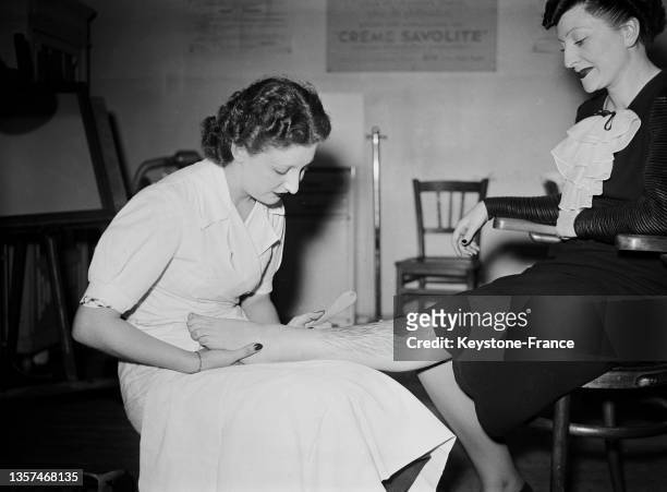 Femme se faisant épiler les jambes dans un institut de beauté, en mai 1937.