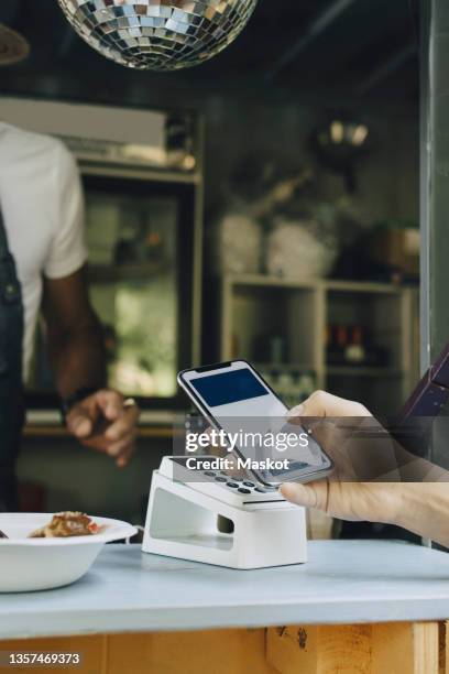 cropped image of man doing contactless payment at counter - contactless payment stock pictures, royalty-free photos & images