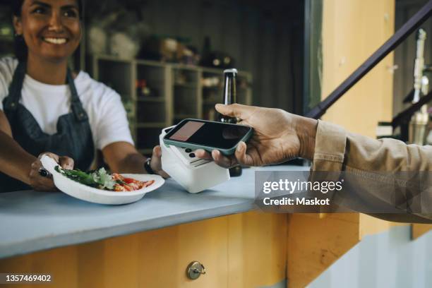 cropped image of customer doing contactless payment at food truck - phone payment stock-fotos und bilder