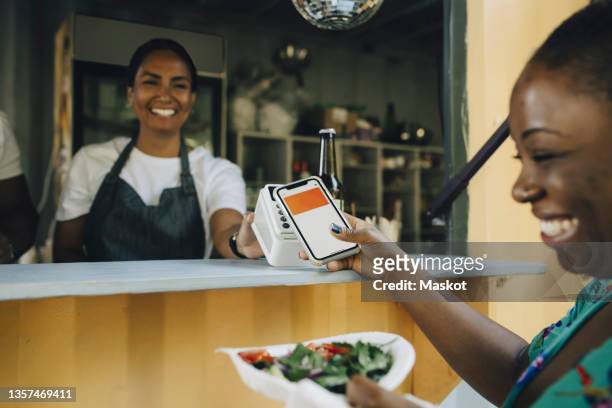happy female customer doing contactless payment at food truck - contactless payment stock pictures, royalty-free photos & images