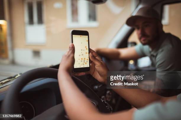 cropped image of delivery woman using smart phone by male coworker in van - gig economy stock pictures, royalty-free photos & images