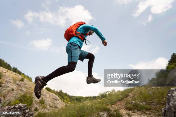 seitenansicht des unkenntlichen engagierten männlichen cross-country-läufers, der den berg hinaufläuft - trailrunning stock-fotos und bilder