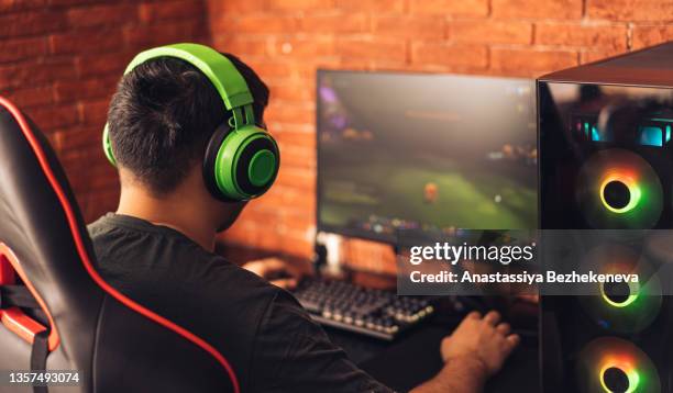 guy plays video games against brick wall - console stock-fotos und bilder