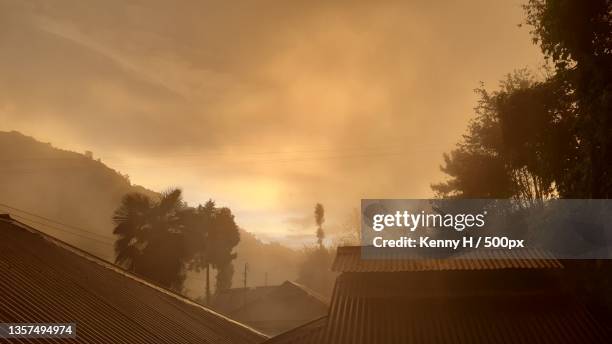 foggy sunset,silhouette of trees and buildings against sky during sunset,jotsoma,nagaland,india - nagaland stock pictures, royalty-free photos & images