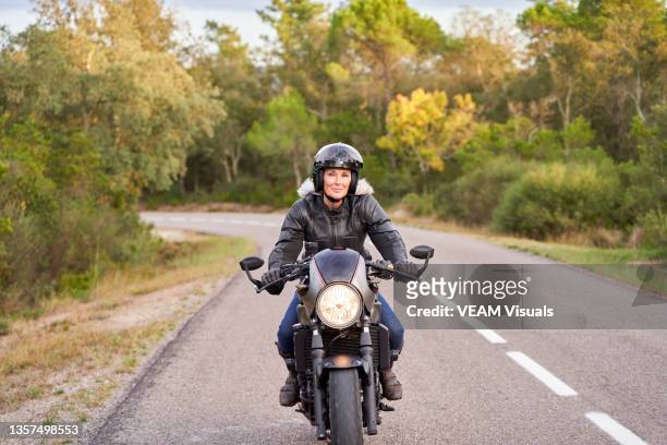 mature woman riding a motorbike on the highway. - adultes moto photos et images de collection