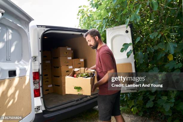 loading an electric van with customer orders of organic vegetable boxes - agriculture supply chain technology stock pictures, royalty-free photos & images