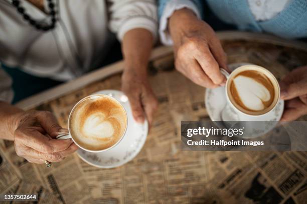 top view of senior women hands enjoying time together indoors in café. - senior women cafe stock pictures, royalty-free photos & images