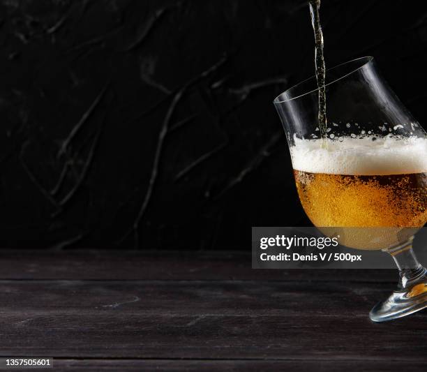 beer pouring into a glass wooden table dark wall - beer white background stock pictures, royalty-free photos & images