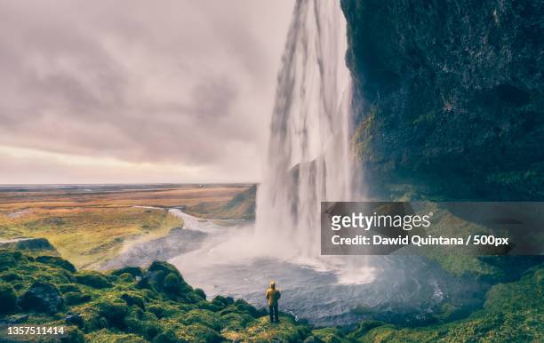 seljalandsfoss,man standing against waterfall,iceland - seljalandsfoss waterfall stock pictures, royalty-free photos & images