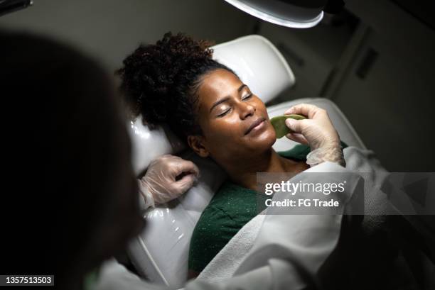 giovane donna che riceve un massaggio facciale in una spa - estetista foto e immagini stock