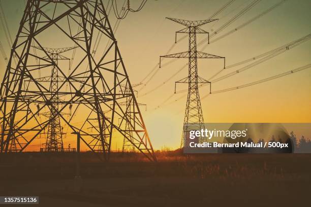 electricity poles among the sunset,low angle view of silhouette of electricity pylon against sky during sunset,toronto,ontario,canada - electricity pylon stock-fotos und bilder