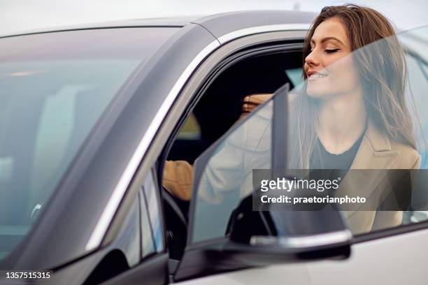 young woman is entering/exiting her car - car leaving stock pictures, royalty-free photos & images
